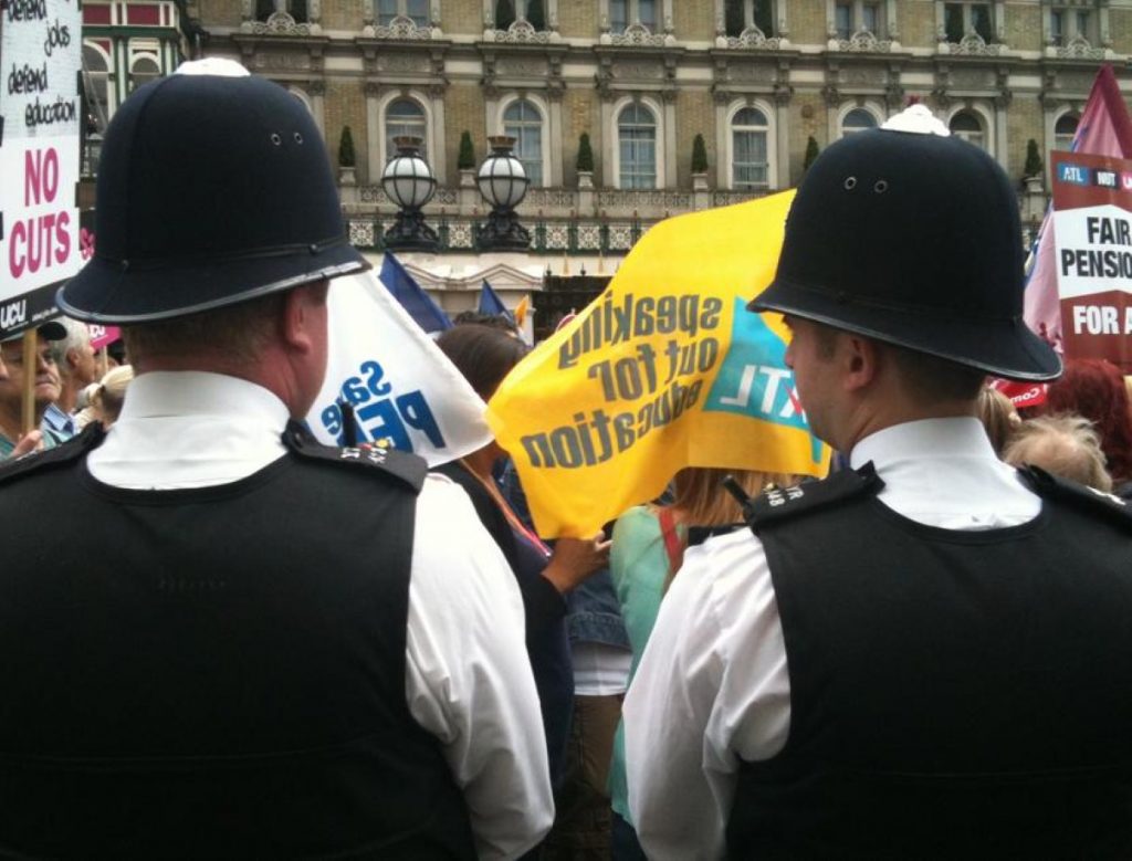 Policemen look on during the public sector strike march