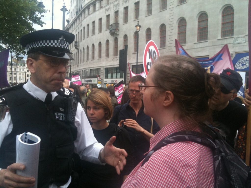 A policeman negotiates with a teacher at a protest for public sector pensions