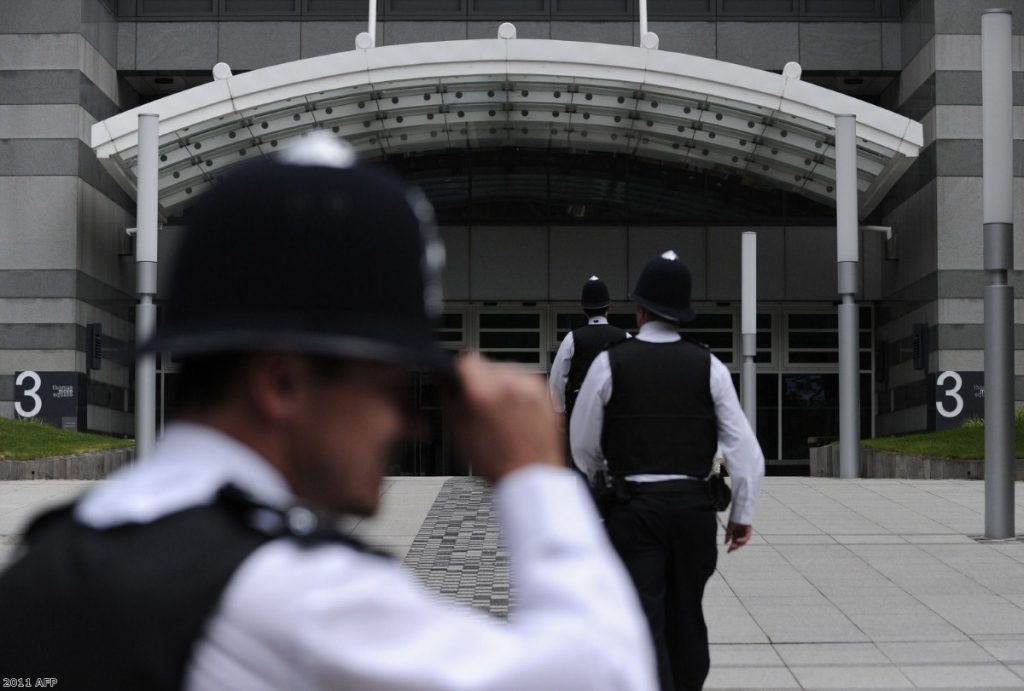 Police officers stand outside the News International offices in east London over the weekend
