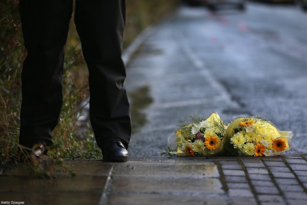 A police officer stands next to a tribute of flowers given by a member of the public in Hattersley, Tameside at the corden where two female police officers were shot.
