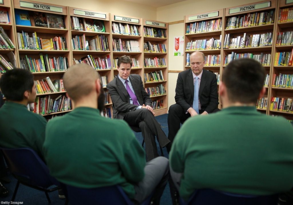 Grayling is flanked by books as he talks to inmates with deputy prime minister Nick Clegg