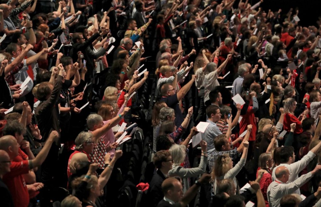 Delegates hold up their fists as they sing the Red Flag after Corbyn