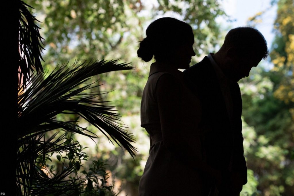 The Duke and Duchess of Sussex wait to speak onstage as they attend a reception during their recent African tour.