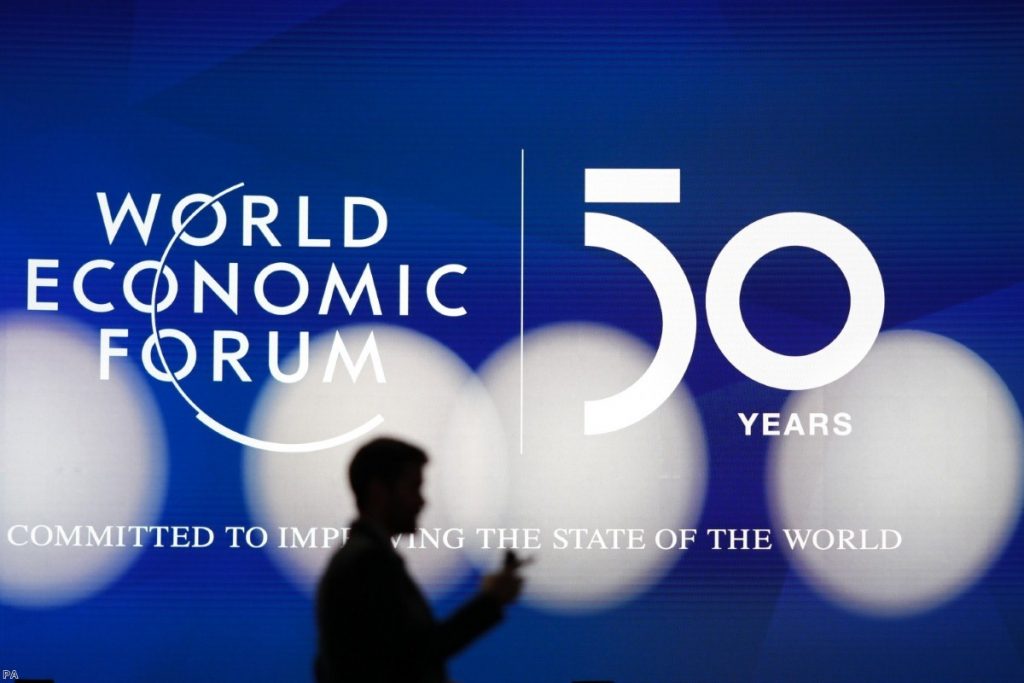 A man silhouettes in front of the logo of the World Economic Forum in Davos, Switzerland, on Sunday.