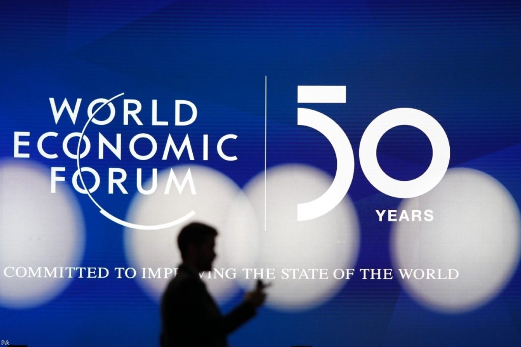 A man silhouettes in front of the logo of the World Economic Forum in Davos, Switzerland, on Sunday. 