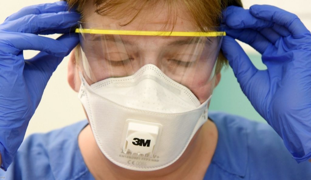A nurse wearing wearing protective equipment puts on her goggles at the Clinic for Infectiology/Tropical Medicine, Nephrology and Rheumatology in Leipzig.