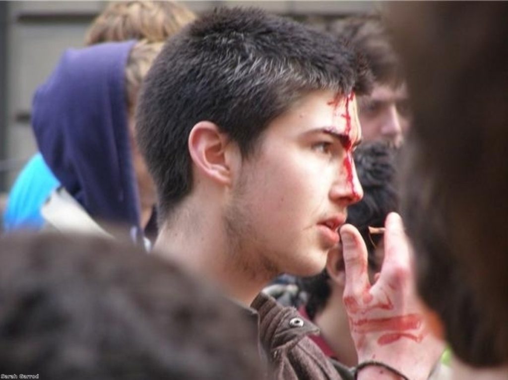 A protestor with blood on his face stares at police lines during the 2009 G20 demonstration in London.