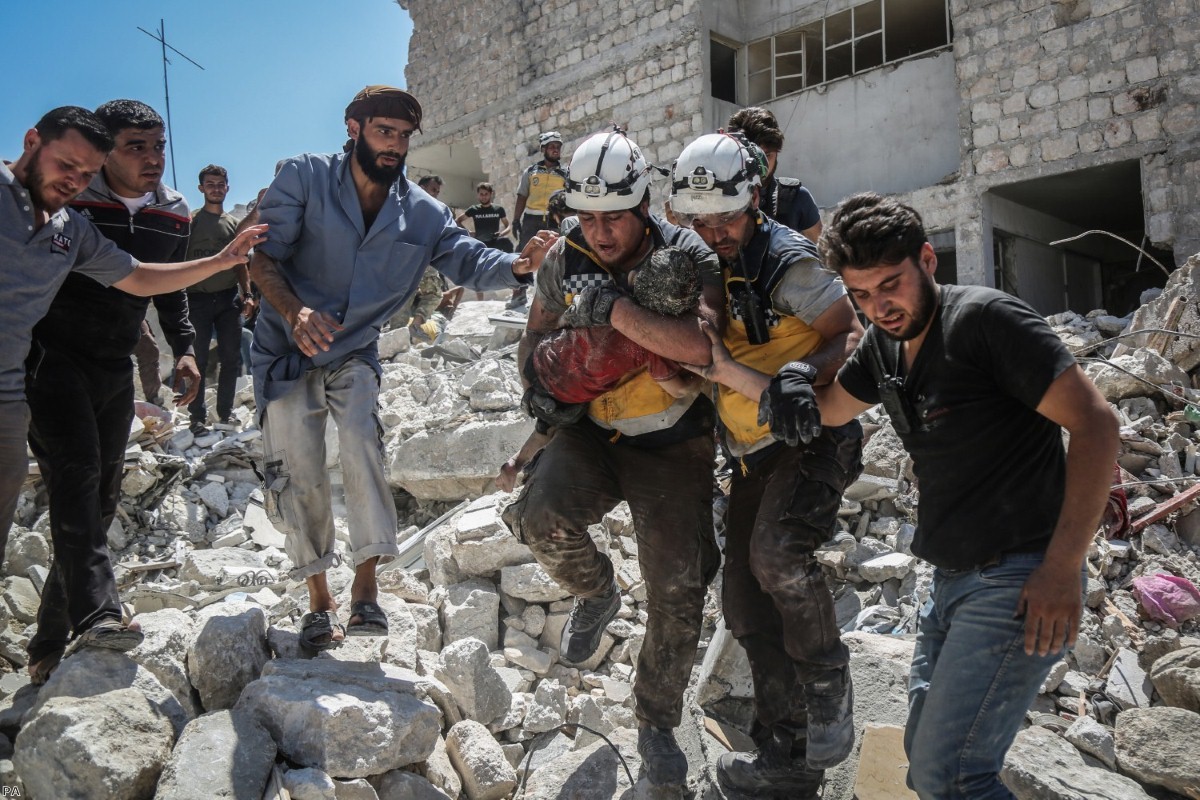 Members of the White Helmets in Syria carry an injured but alive child from the rubble of a collapsed building following pro-regime air strikes in summer last year.