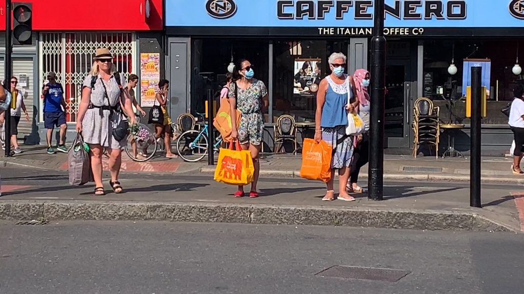 People standing at traffic lights wearing face masks