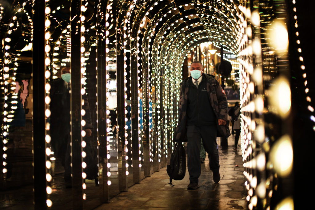 A man walks through an illuminated walkway in Covent Garden, London, which has moved into the highest tier of coronavirus restrictions as a result of soaring case rates.