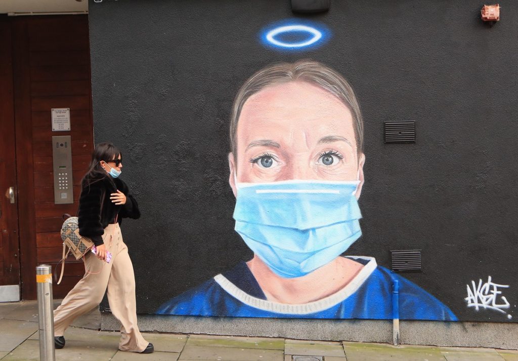 A woman walks past a mural in Manchester city centre. Cities in northern England and other areas suffering a surge in Covid-19 cases may have pubs and restaurants temporarily closed to combat the spread of the virus.