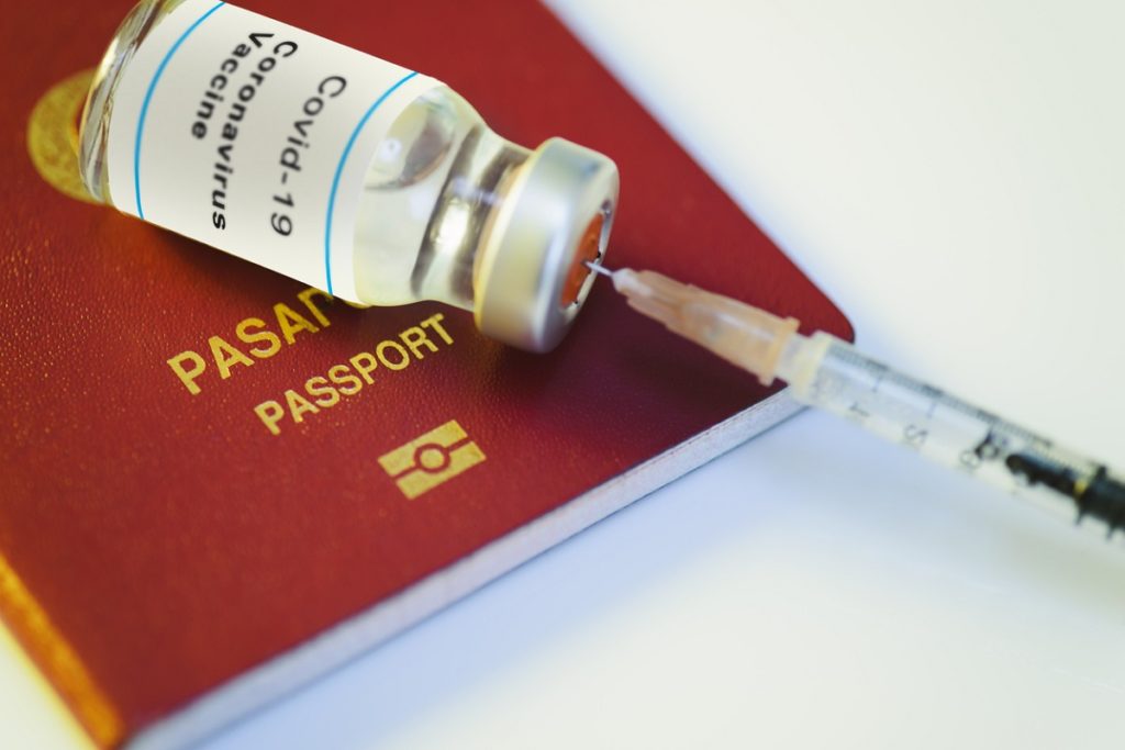 Close up shot of a coronavirus vaccine bottle with a passport.